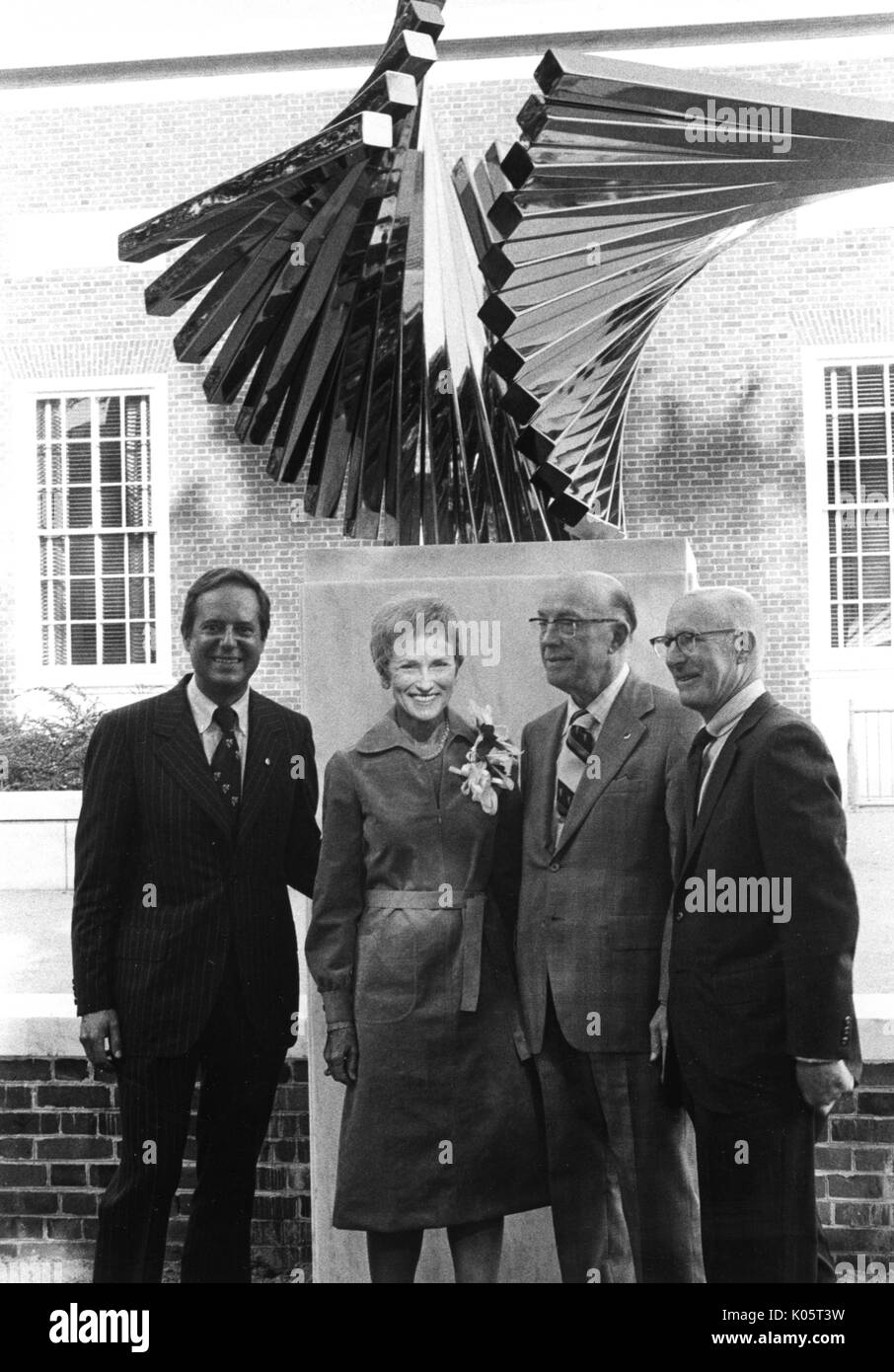 Steven Muller y otras tres personas no identificadas que se encuentran frente a una estatua de arte en la Universidad Johns Hopkins durante la ceremonia de apertura del Centenario. 1970. Foto de stock