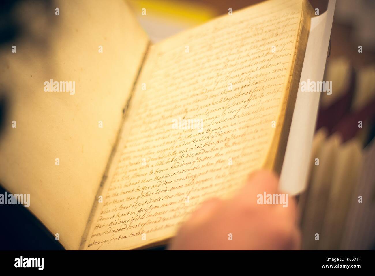 Una sobre el hombro del disparo de un estudiante universitario mantiene abierto un libro antiguo, de 2016. Foto de stock