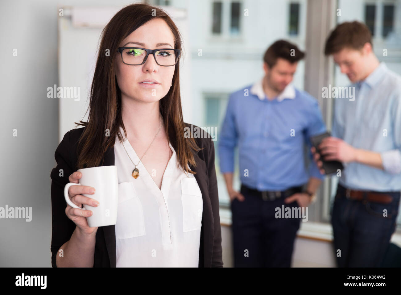 La empresaria mantiene taza de café mientras los colegas debatiendo en Foto de stock