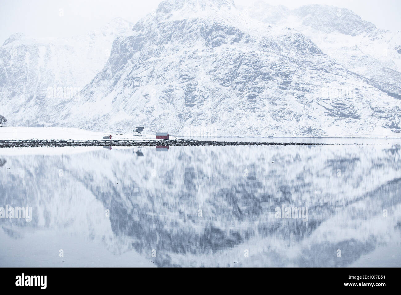 Reflejo perfecto de las montañas y la casa roja, Islas Lofoten, Noruega Foto de stock