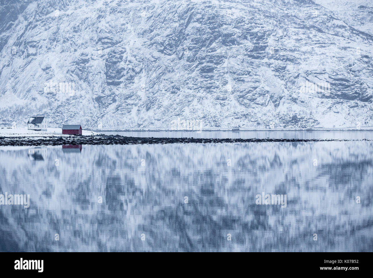 Reflejo perfecto de las montañas y la casa roja, Islas Lofoten, Noruega Foto de stock