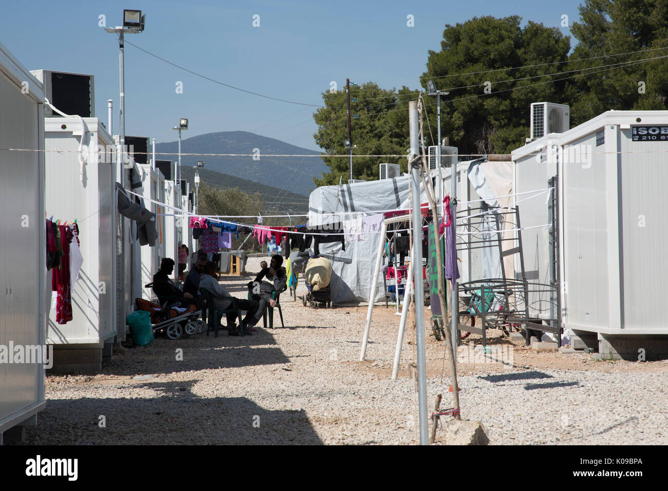 Los hombres sentados a la sombra entre las filas de las unidades prefabricadas de alojamiento en campamento de refugiados Ritsona, Grecia. Foto de stock