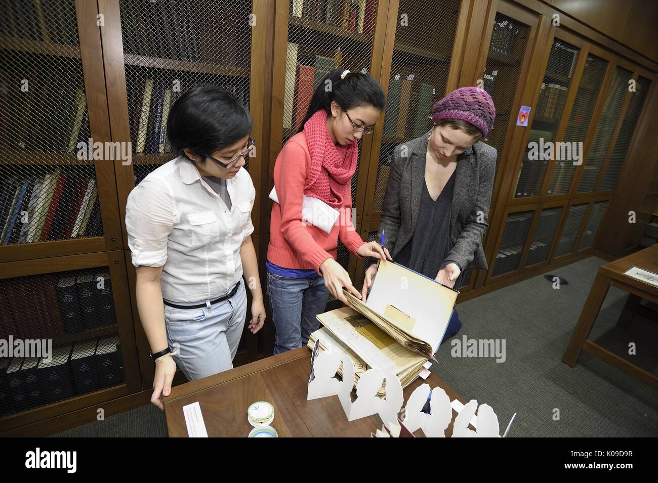Tres mujeres estudiantes universitarios están empezando a mirar a través de un cuaderno de la biblioteca en el evento llamado sucio Libros y anhelo mira, 11 de febrero de 2016. Foto de stock