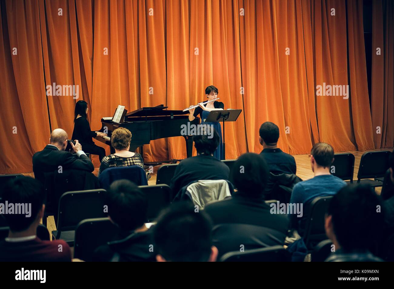 Dos estudiantes universitarios femeninos Johns Hopkins la realización de flauta y piano en frente de una audiencia, en el año 2015. Cortesía de Eric Chen. Foto de stock