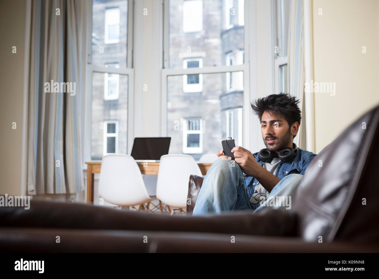 Hombre asiático usando su teléfono en casa en el salón. Foto de stock
