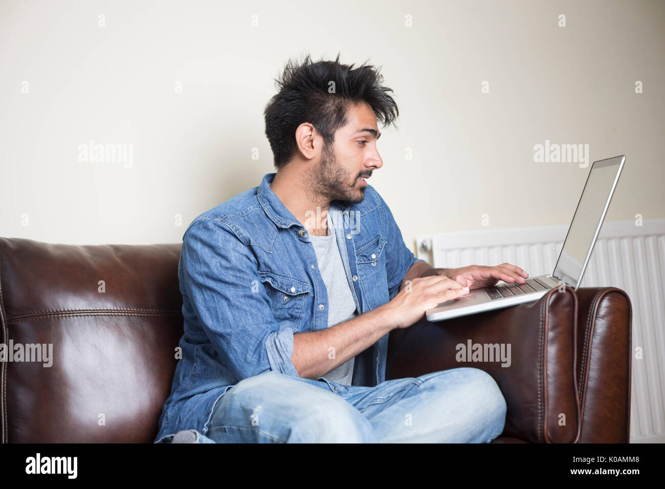 Hombre asiático con portátil en casa en el salón. Foto de stock