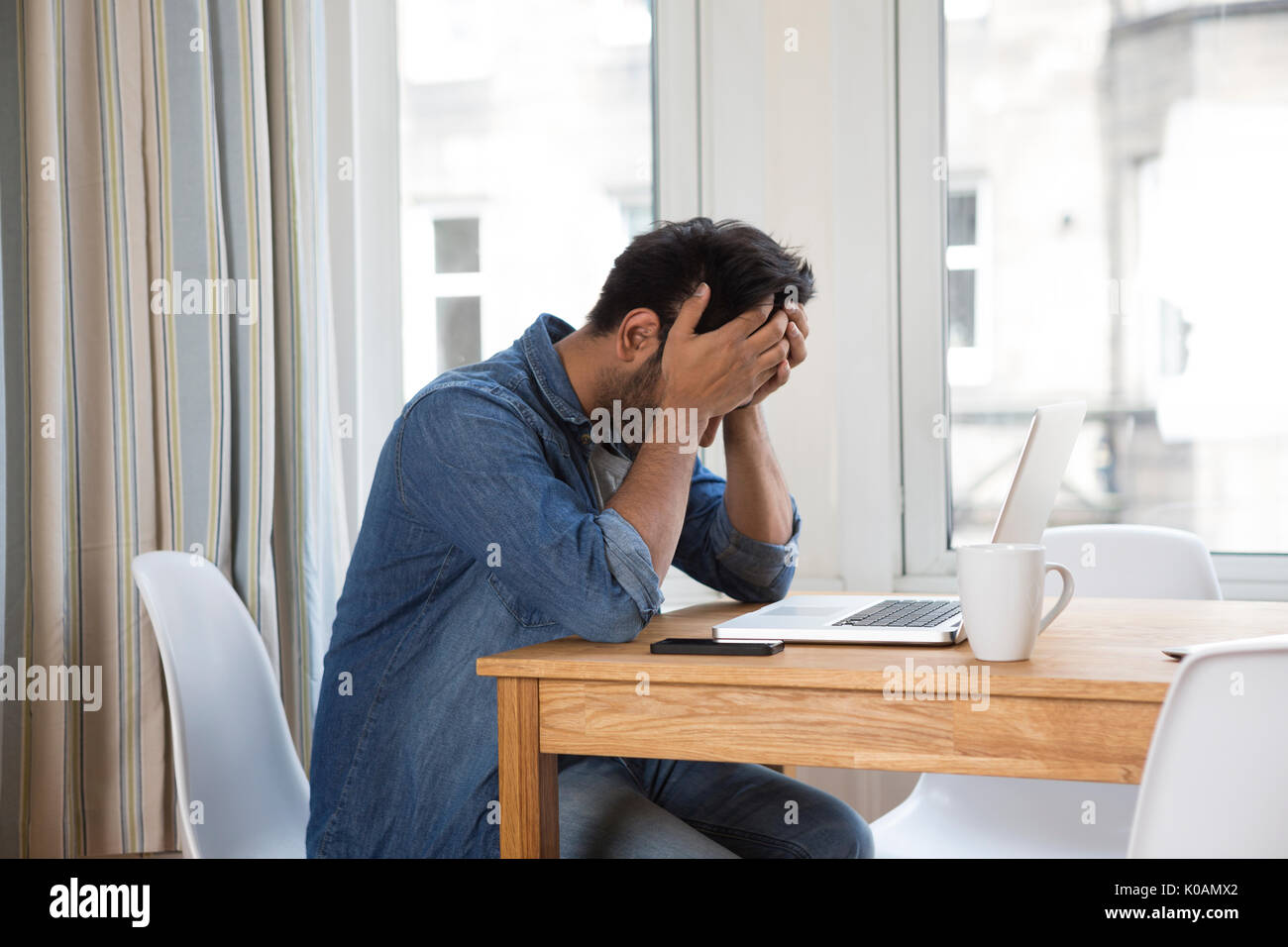 Estresado y frustrado hombre asiático sentado en su ordenador portátil. Foto de stock