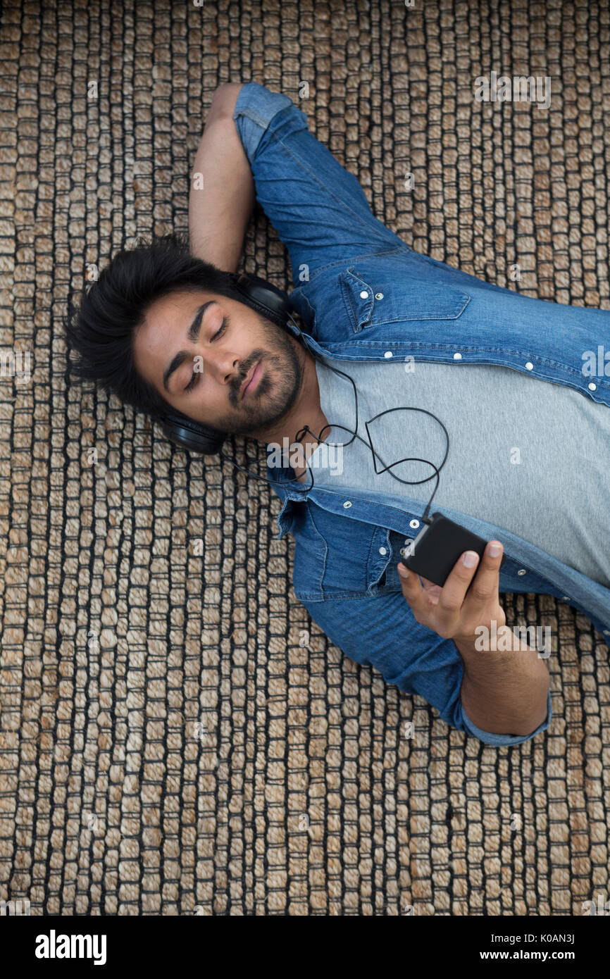 Indian hombre tumbado en el suelo en casa la lectura de su Tablet PC. Vista anterior. Foto de stock