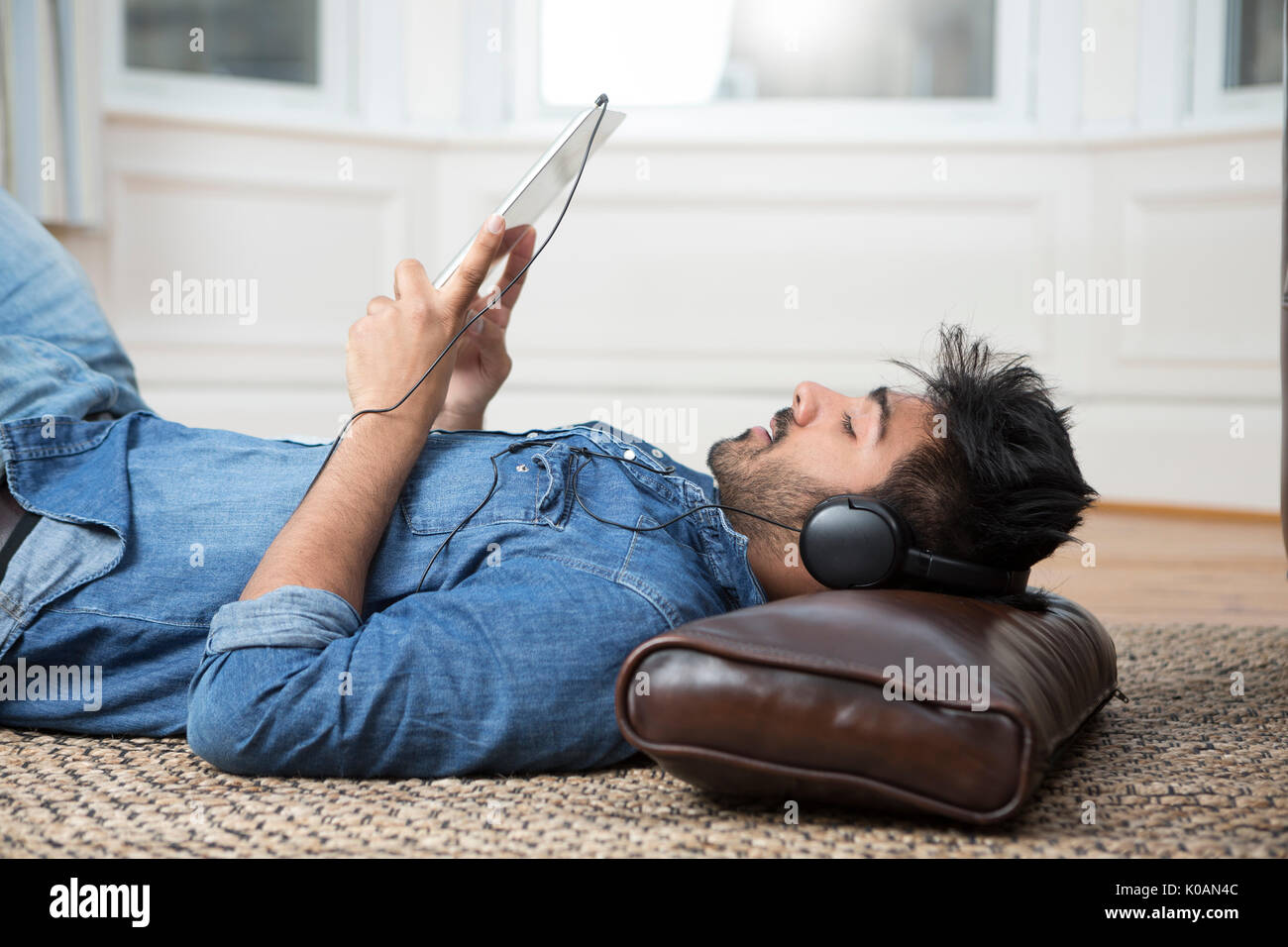 Hombre asiático acostado en el piso en el hogar y el uso de un Tablet PC. Foto de stock