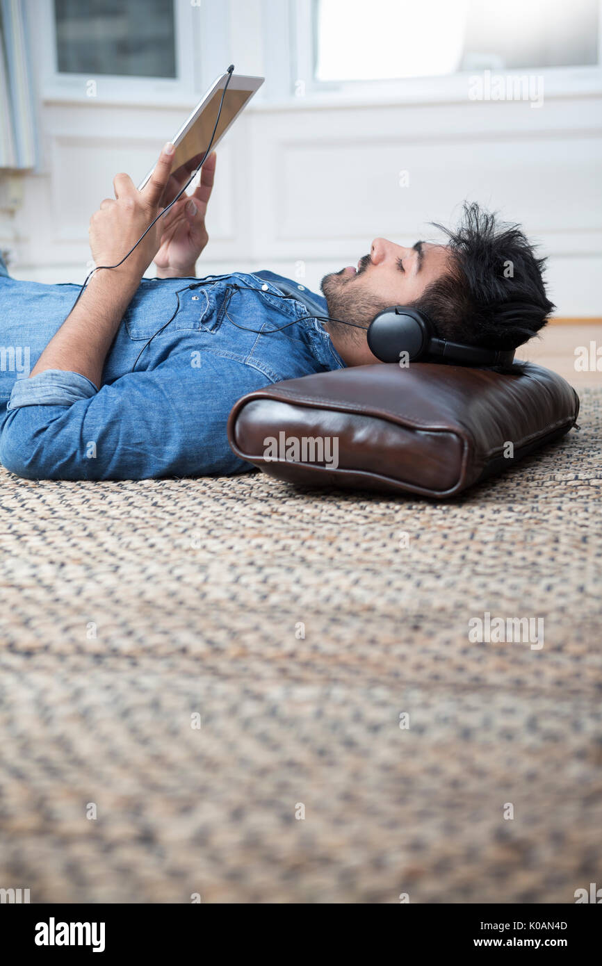Hombre asiático acostado en el piso en el hogar y el uso de un Tablet PC. Foto de stock