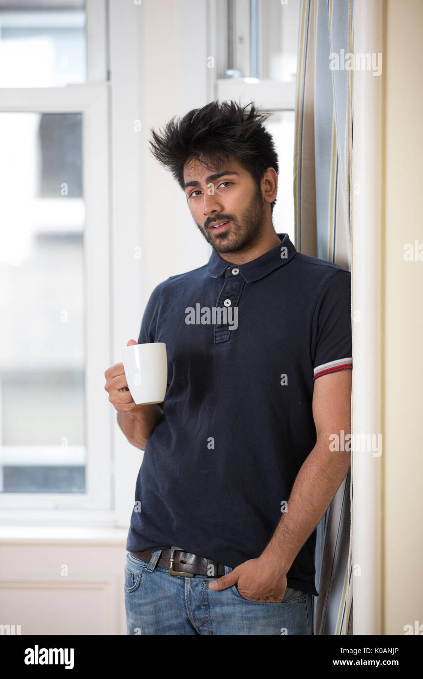 Retrato de un hombre asiático en casa beber una taza caliente de café o té. Foto de stock