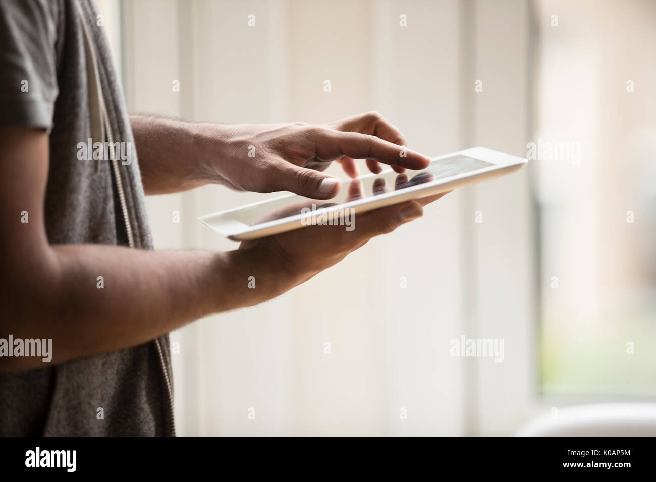 Vista cercana de un hombre asiático mediante tableta digital en casa. Foto de stock