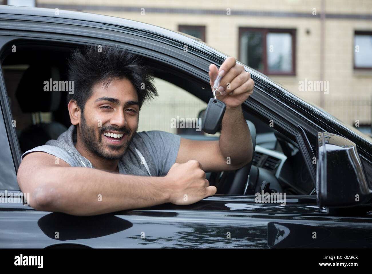 Retrato de un hombre sonriente indio feliz en su nuevo coche y manteniendo pulsada la tecla. Foto de stock