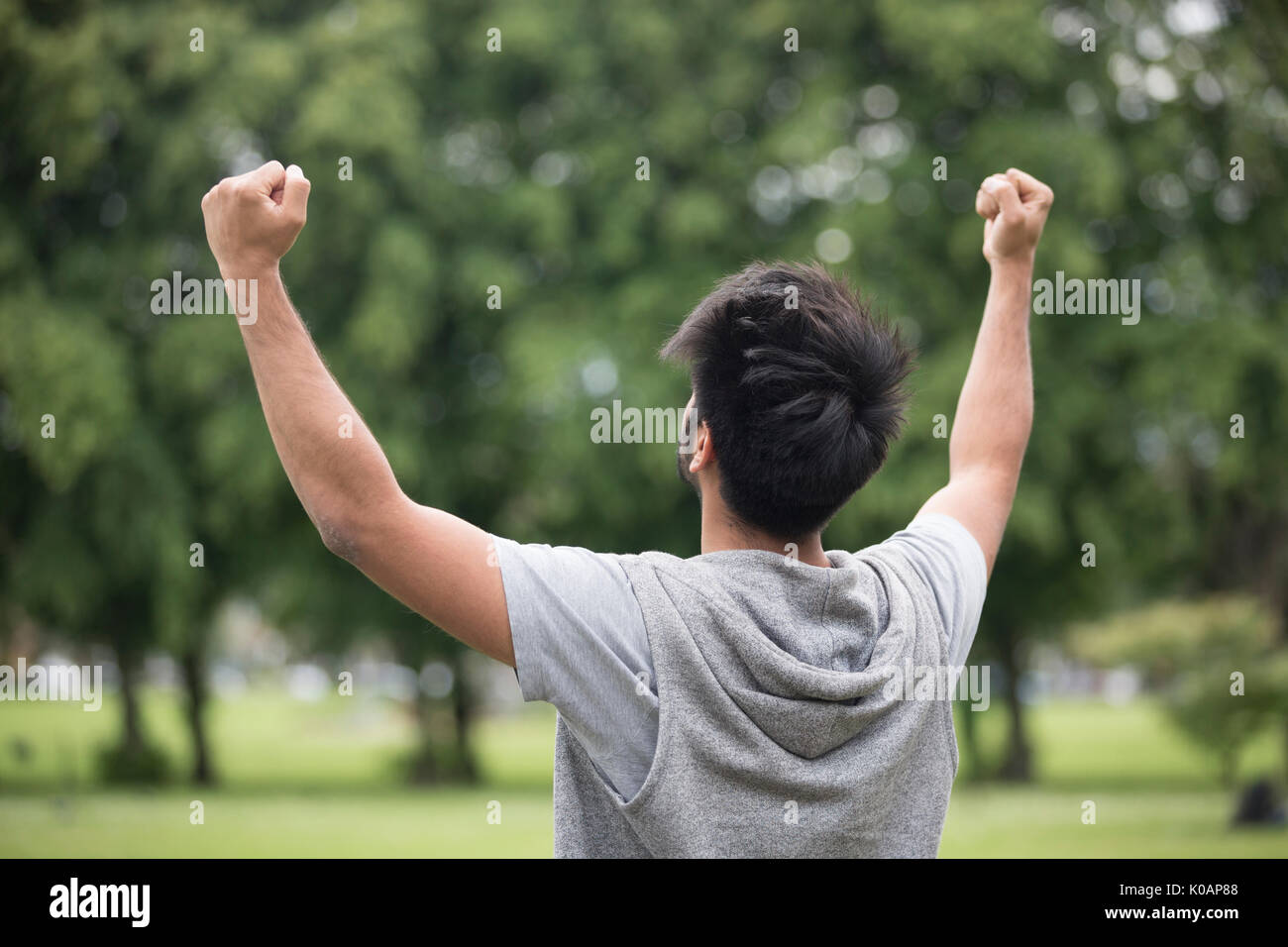 Hombre asiático de pie con los brazos levantados al aire libre. Concepto de libertad, de fe y de fiesta. Foto de stock