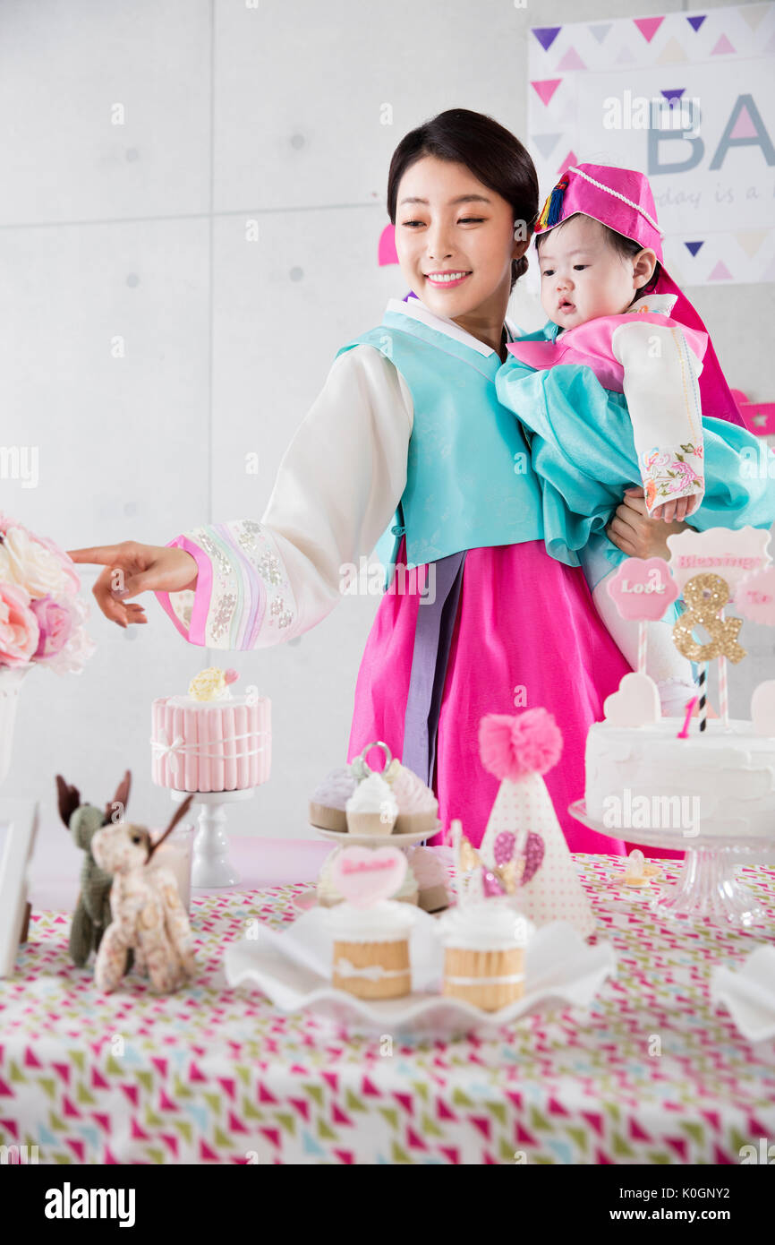Coreano sonriente hija de la madre y del bebé en la primera fiesta de cumpleaños Foto de stock