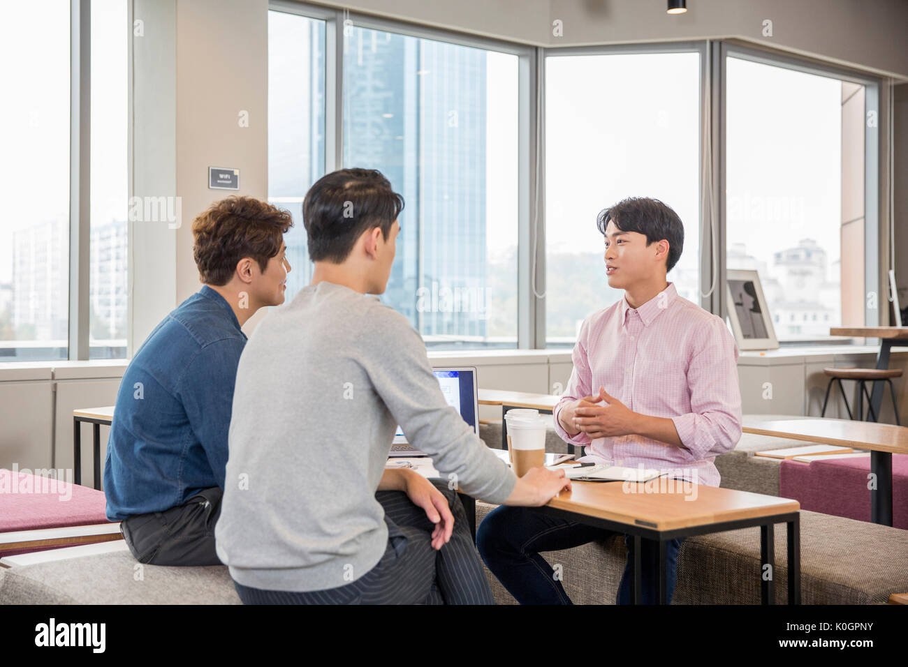 Tres empresarios sonrientes tener conversaciones en cafetería Foto de stock