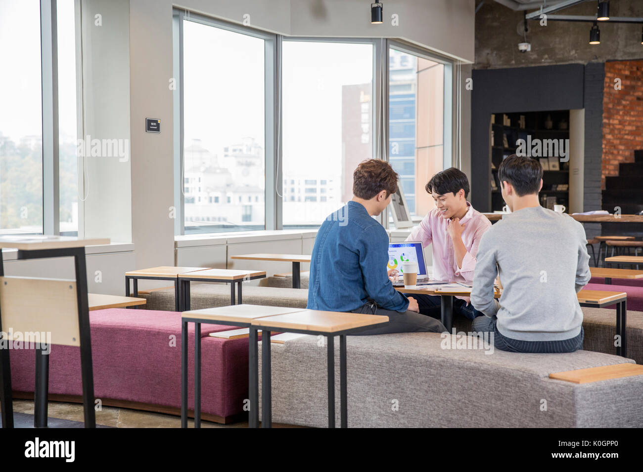 Tres empresarios sonrientes tener conversaciones en cafetería Foto de stock
