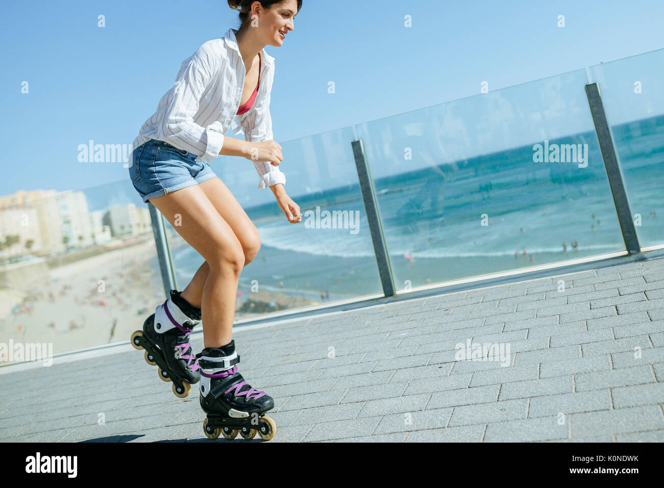 Mujer joven de patinaje en línea en el paseo marítimo en la costa  Fotografía de stock - Alamy