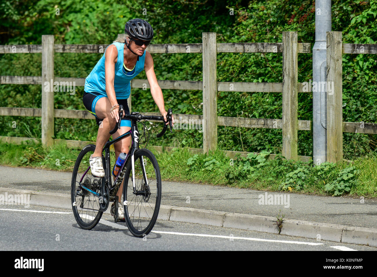 Una ciclista que monta a velocidad en una carretera en Newquay en Cornualles. Foto de stock
