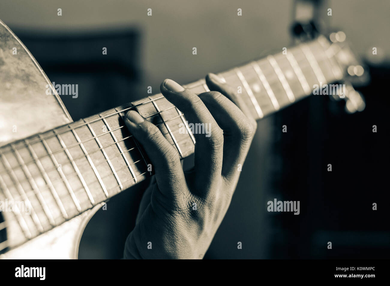 Cerrar a mano tocando la guitarra en tono blanco y negro Foto de stock
