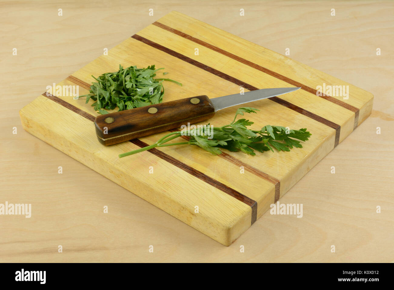 Perejil fresco picado con cuchillo de cocina tabla de cortar de madera Foto de stock