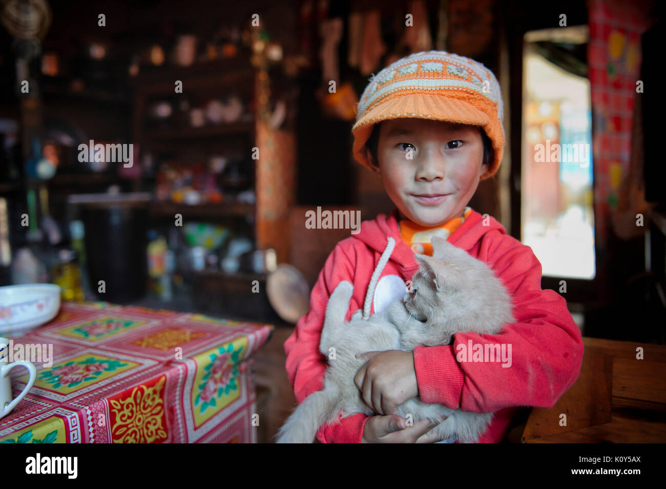 Niño tibetano jugando con su mascota en su casa. Meseta Tibetana Foto de stock