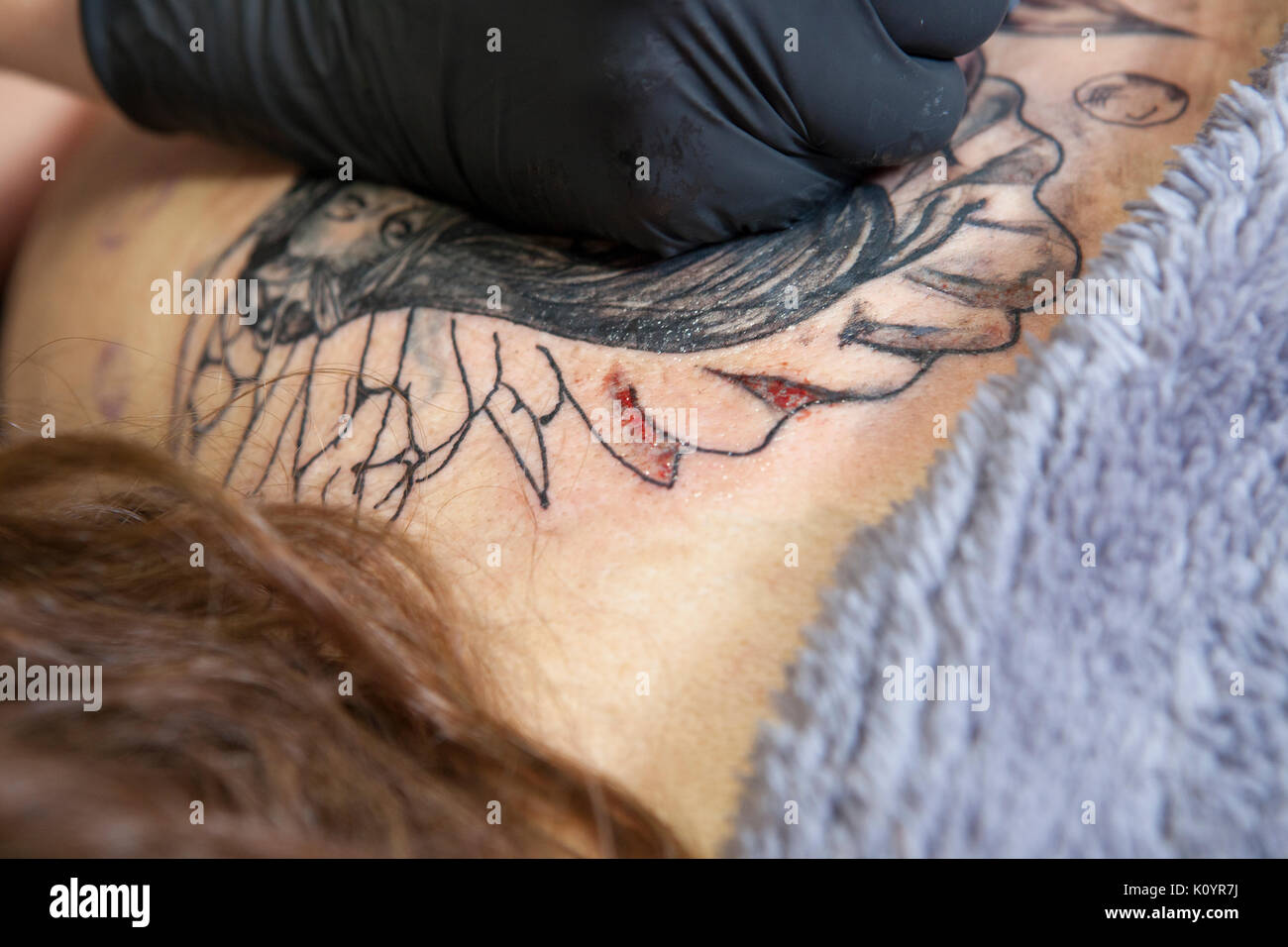 Artista Femenina del tatuaje se aplica para el omóplato de una mujer  cliente. Primer plano de la tinta del lápiz máquina inyectando tinta negra  Fotografía de stock - Alamy