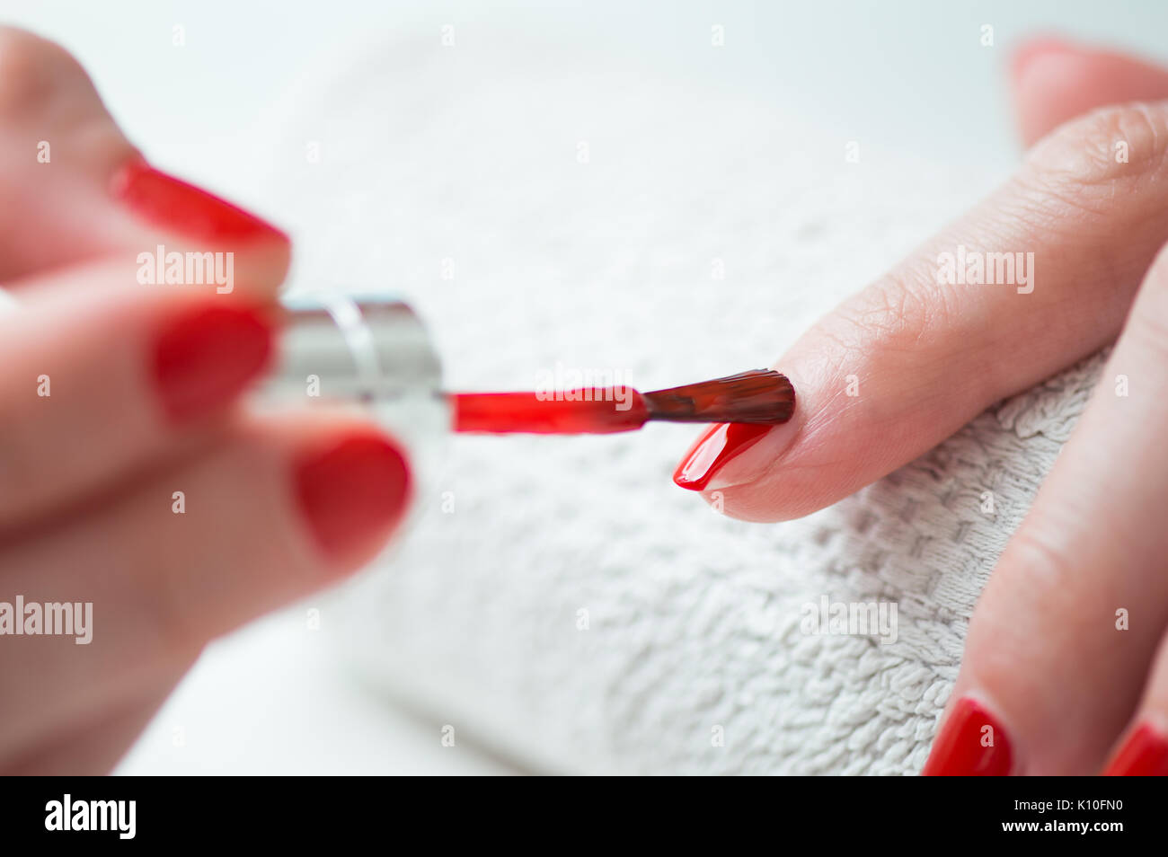 Primer plano de una mujer pintar sus uñas con esmalte de uñas de color rojo Foto de stock