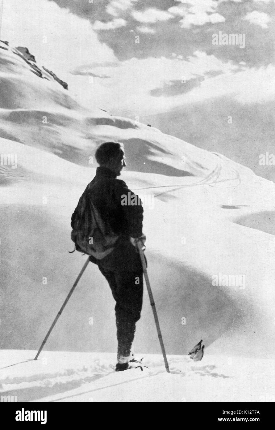 Hombre con gafas de sol posa con esquí y otros equipos en la cima de la  montaña