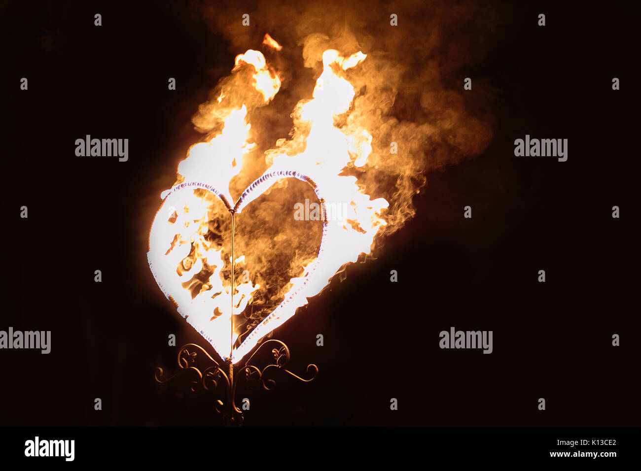 Fuego, sentimientos, simbolismo concepto. en la oscuridad hay un gran corazón cubierto en llamas de color naranja brillante como símbolo del amor que siempre gana w Foto de stock