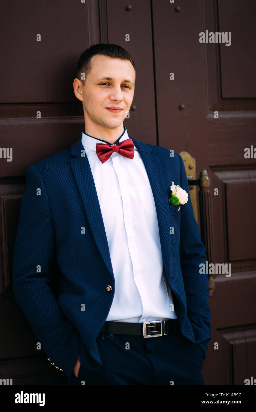 Traje de novio vestidos de azul y pajarita en la puerta roja Fotografía de  stock - Alamy