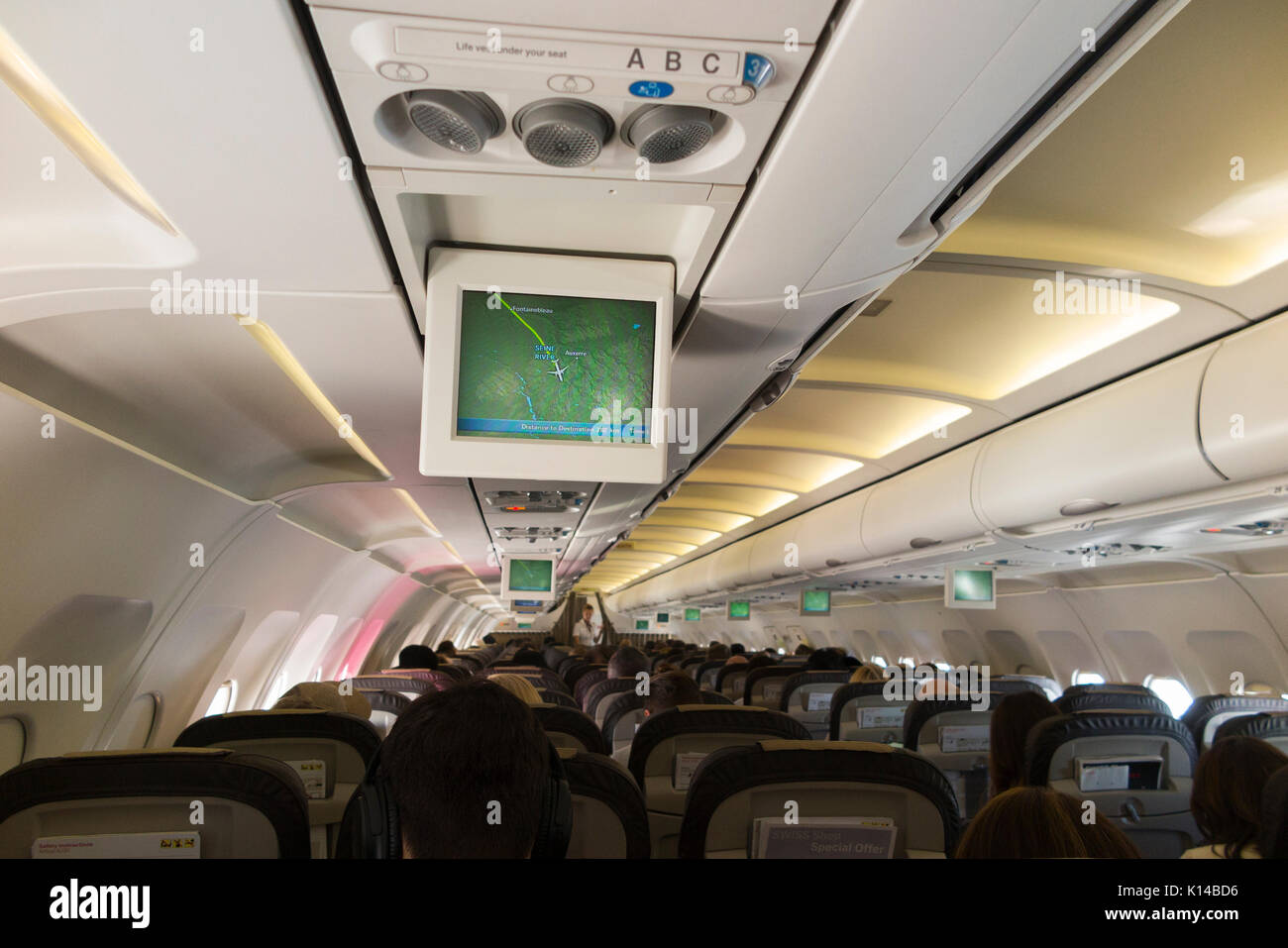 Dentro de un avión / interior de la cabina de un avión con el monitor de visualización de mapa de la posición de vuelo en una pantalla de televisión que muestra la posición de aviones arriba / sobre Francia. Foto de stock