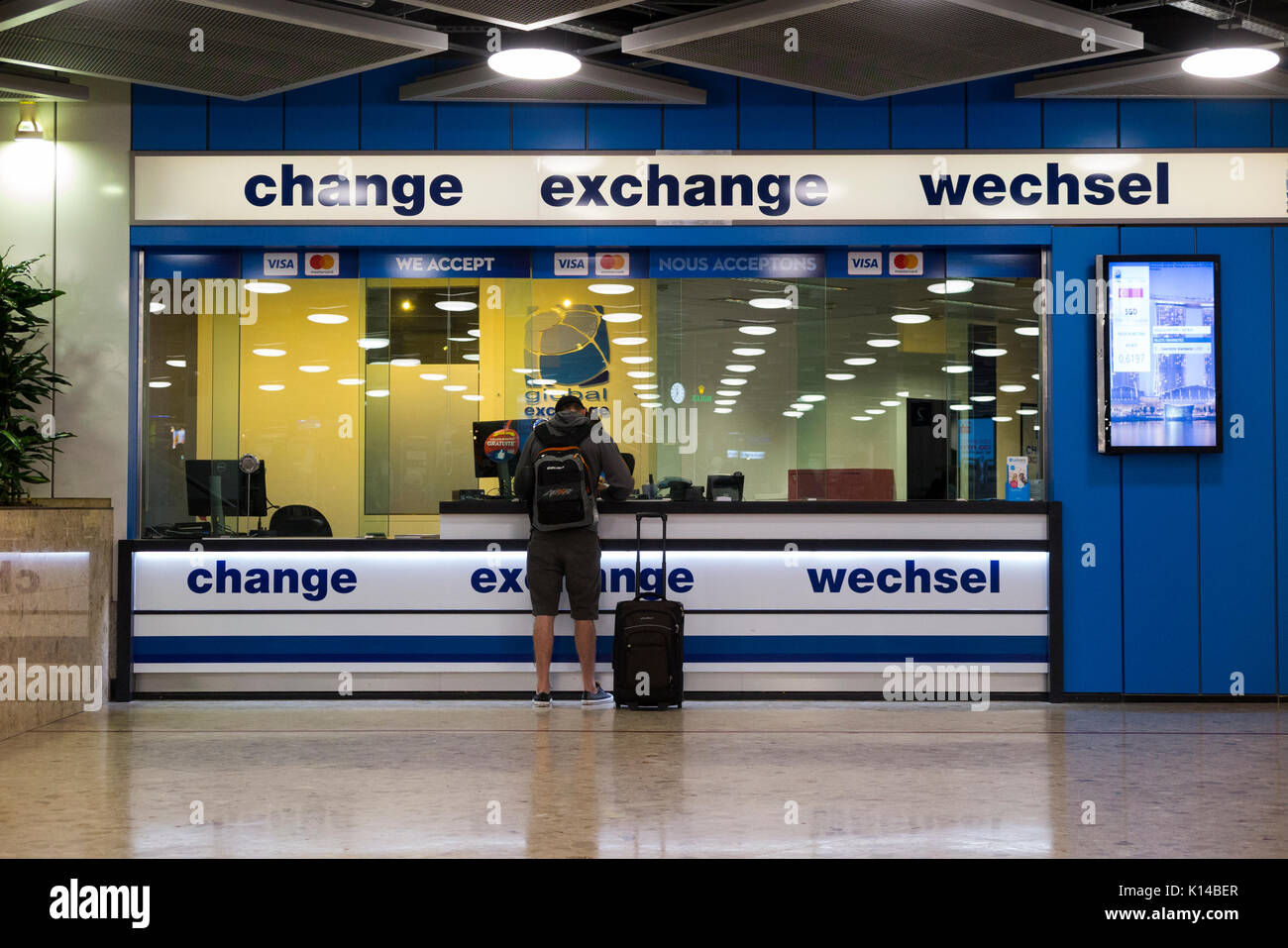 Los servicios de cambio de divisas Global Exchange Bureau de Change (y cliente), en el área de reclamo de de llegadas del aeropuerto de Ginebra. Suiza Fotografía de stock -