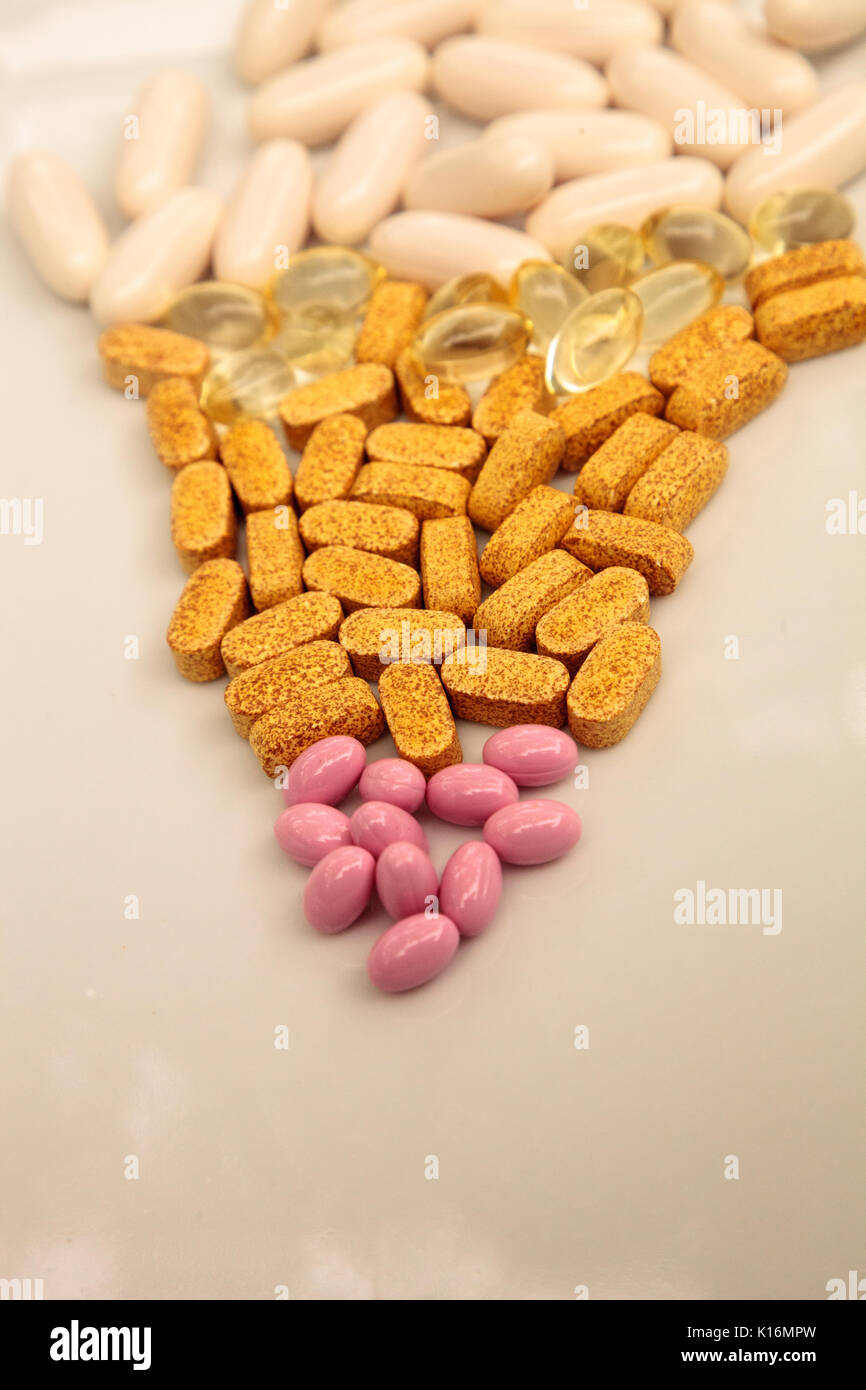 Mezcla de oro, rosa y blanco cápsulas de gel de vitamina B, vitamina E, vitamina  D, biotina y Co Q-10 aparece en una superficie blanca Fotografía de stock -  Alamy