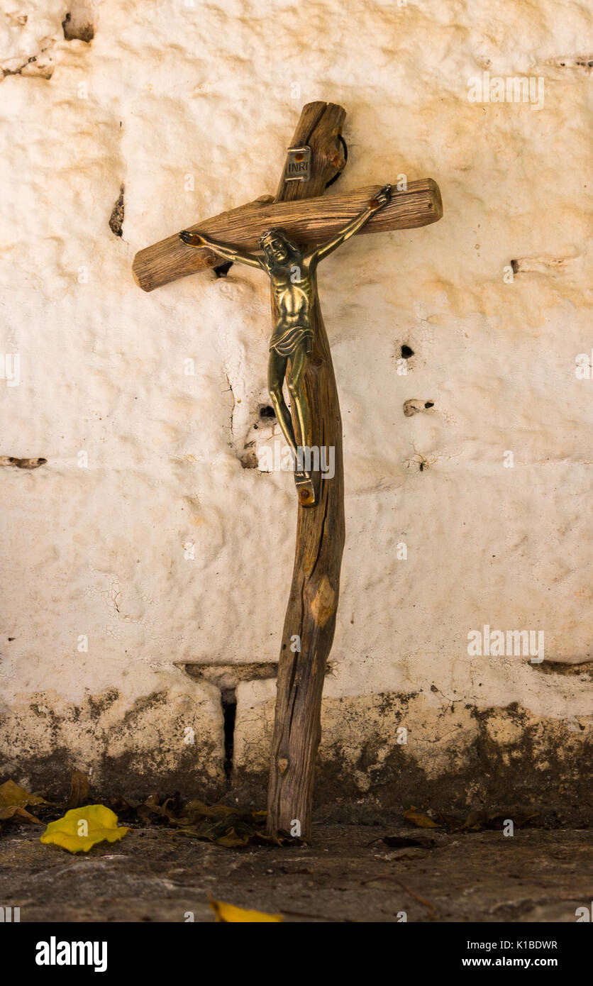 Cerca de religiosos de madera antigua cruz con Jesús metálico apoyarse contra la pared blanca Foto de stock