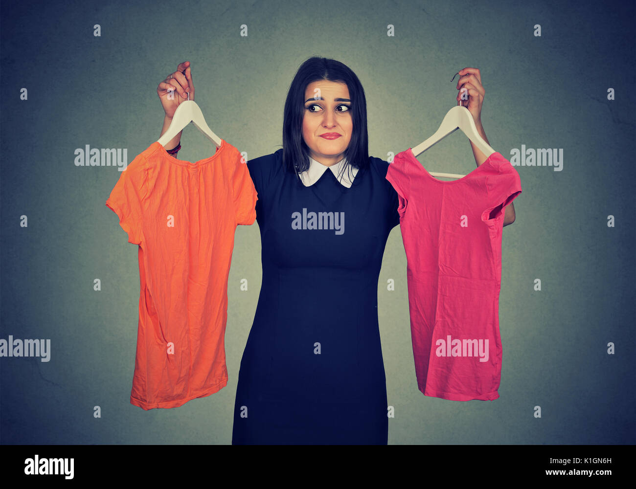 Confundirse mujer elegir entre vestidos y no puede hacer la decisión. Foto de stock