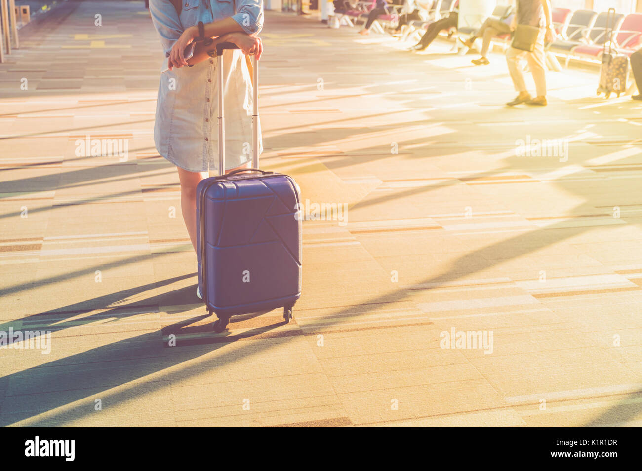 Joven Mujer casual desgaste zapatillas blancas de pie con maleta de viaje  con la luz del sol de la mañana a través de la ventana a la terminal del  aeropuerto,concepto de vacaciones