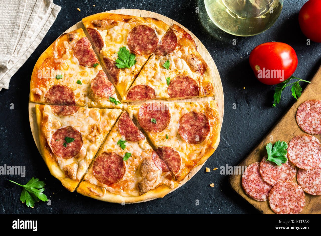 Pizza de pepperoni con ingredientes frescos - pizza casera con pepperoni, queso y la salsa de tomate y los ingredientes en rústica de piedra con fondo negro Foto de stock