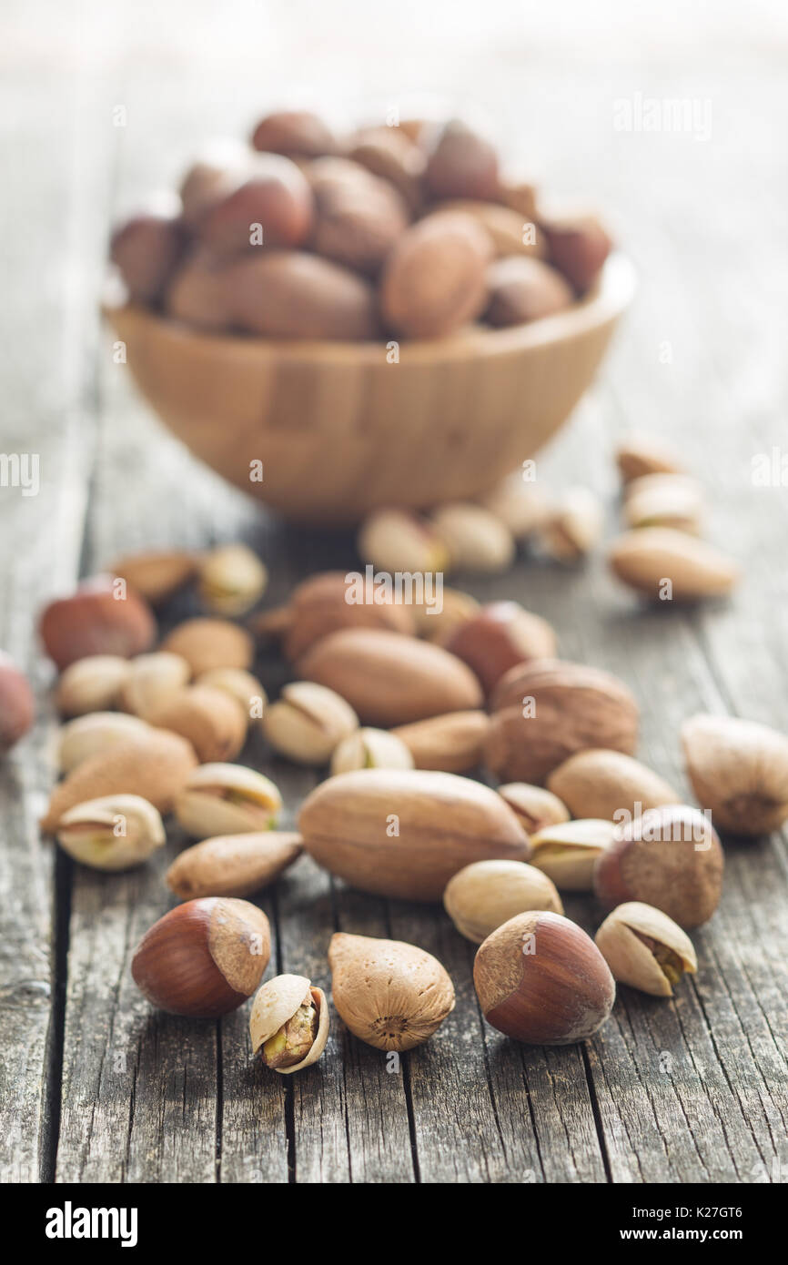 Los diferentes tipos de frutos secos en la cáscara de nuez. Las avellanas, nueces, almendras, nueces de nogal y los pistachos en la mesa de madera antigua. Foto de stock