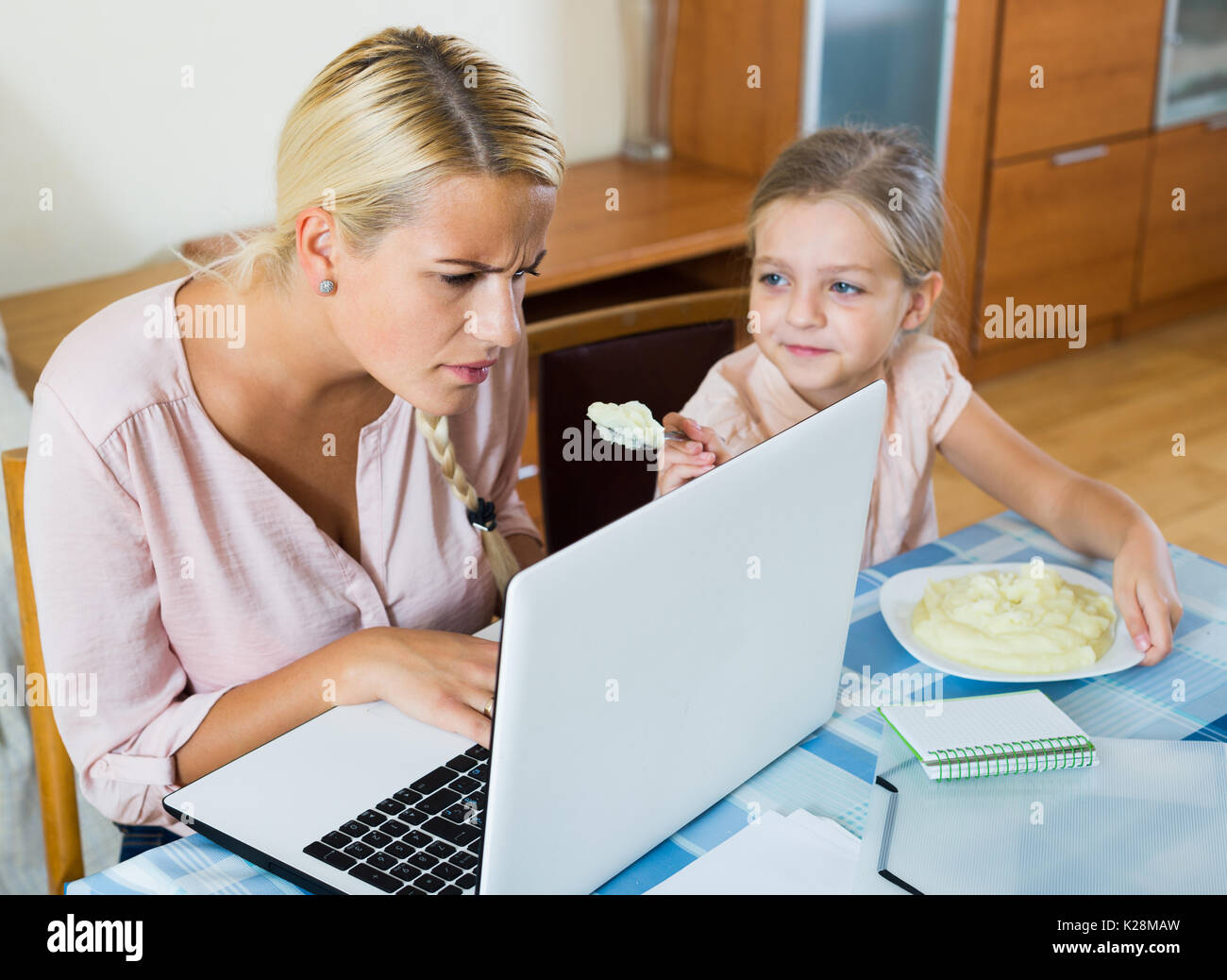 Subrayó la mujer americana que trabaja desde casa, pequeña hija pidiendo atención centrada en la mujer Foto de stock