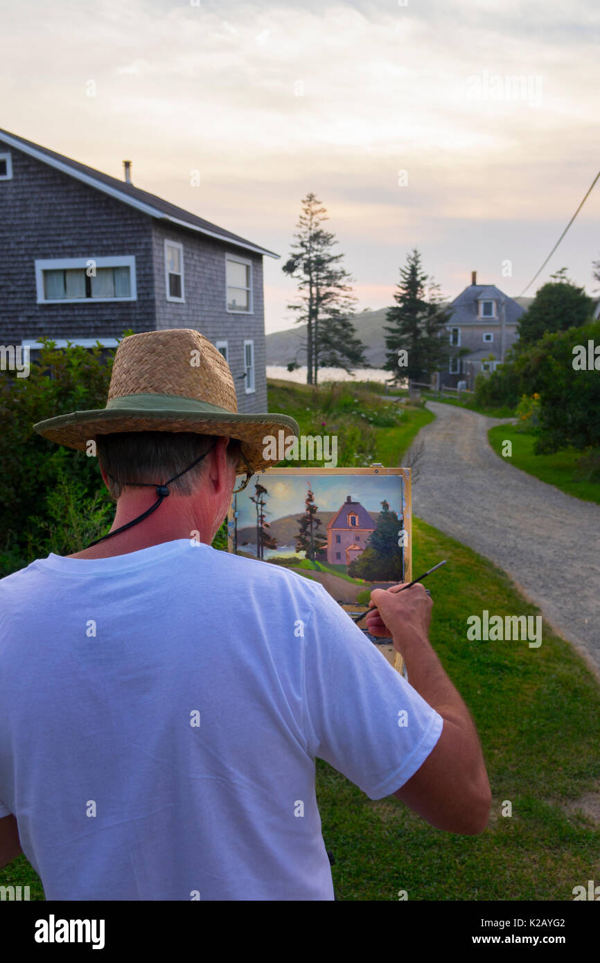 Estados Unidos Maine ME Isla Monhegan un artista es pintar una casa de un camino de grava en el final del día. Foto de stock