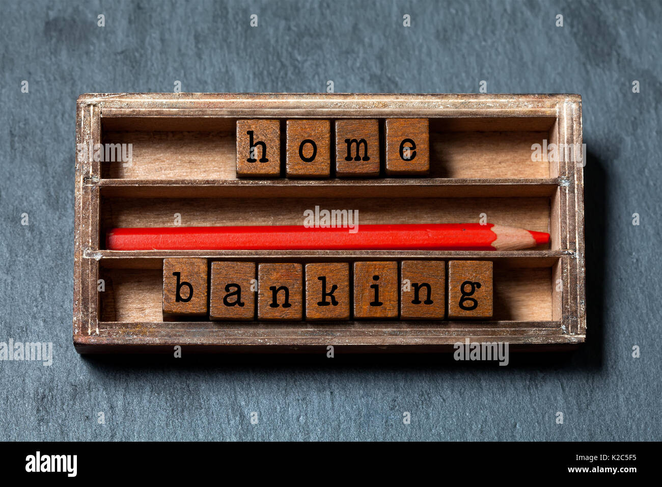 Home banking, concepto de presupuestación de imagen. Las cajas de madera con letras, lápiz rojo, con edad de verificación. Fondo de piedra gris, macro soft focus Foto de stock
