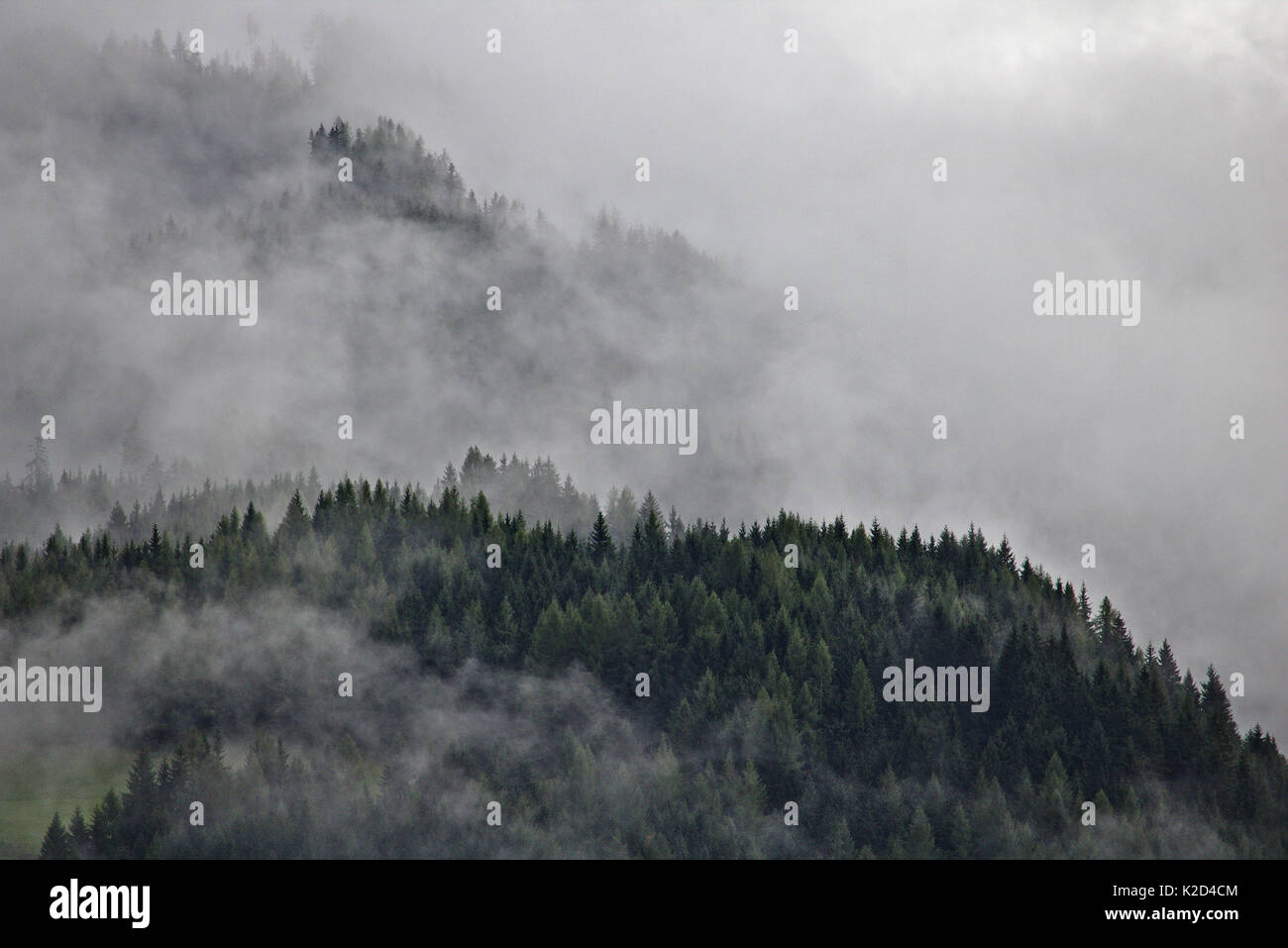 Las crestas de las montañas de los Alpes austriacos parte oscurecida por la niebla y las nubes Foto de stock