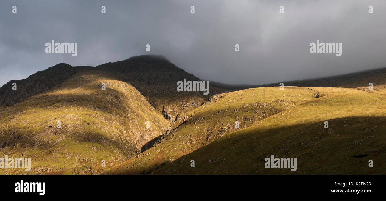 Nube de lluvia formando una espesa niebla descendente desde la escarpada montaña en luz del atardecer al atardecer en Glen Coe, Argyll, Scottish Highlands, Escocia, Reino Unido, septiembre de 2016. Foto de stock