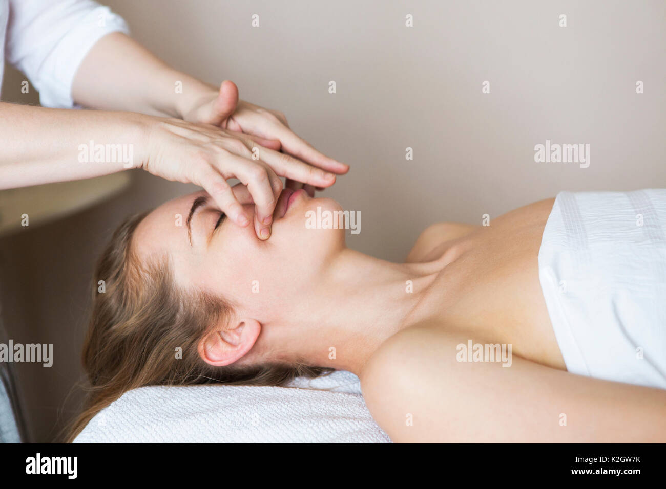 Joven mujer bonita cara masaje o tratamiento de belleza en el salón spa Foto de stock