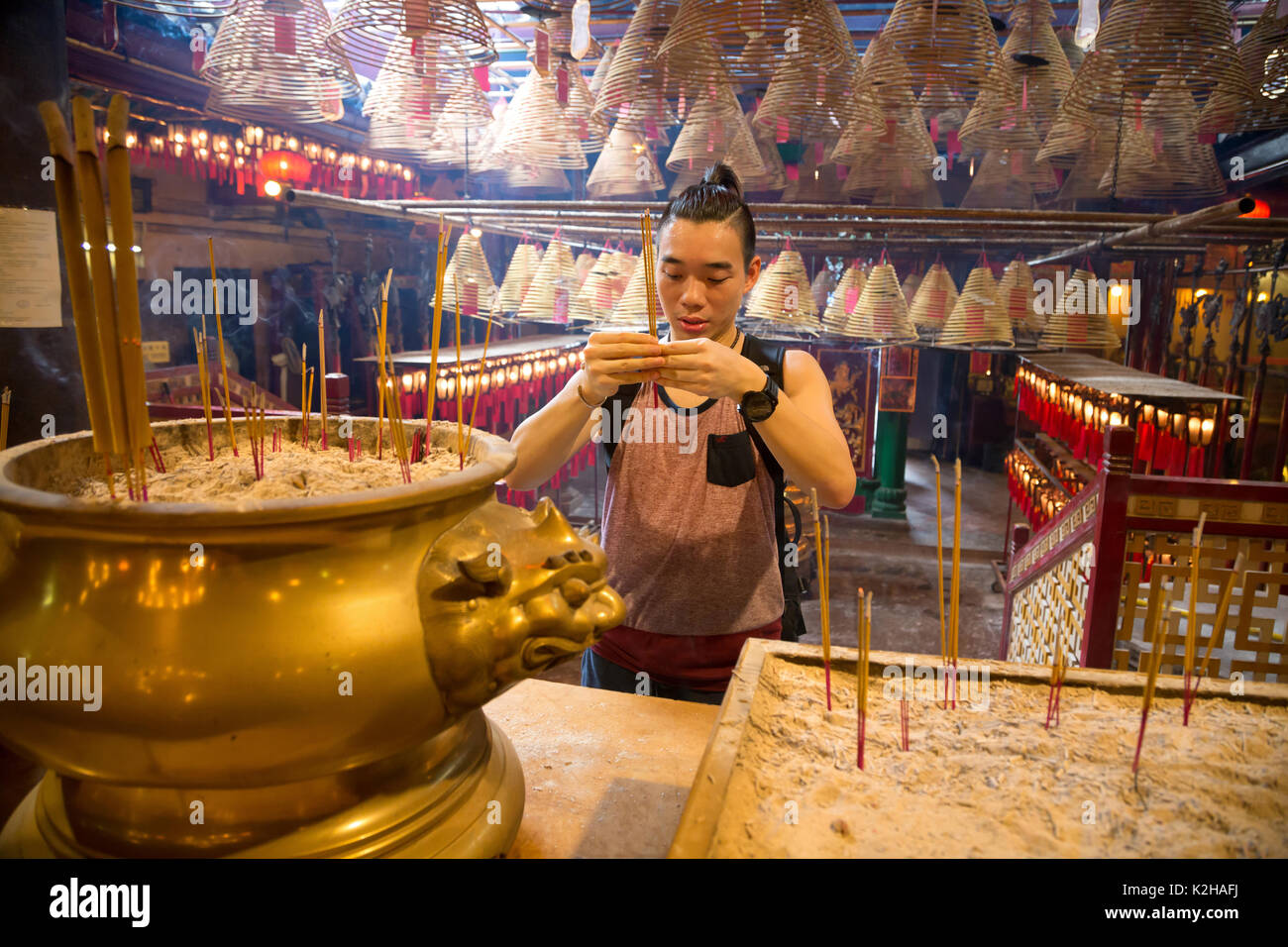 Un hombre joven ora en el templo de Man Mo, en la isla de Hong Kong Foto de stock
