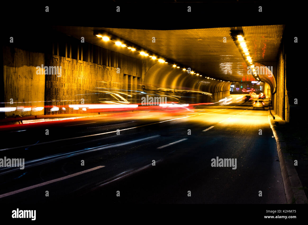 Tráfico nocturno en las calles de la ciudad. Los vehículos para entrar y salir del túnel en el desenfoque de movimiento Foto de stock
