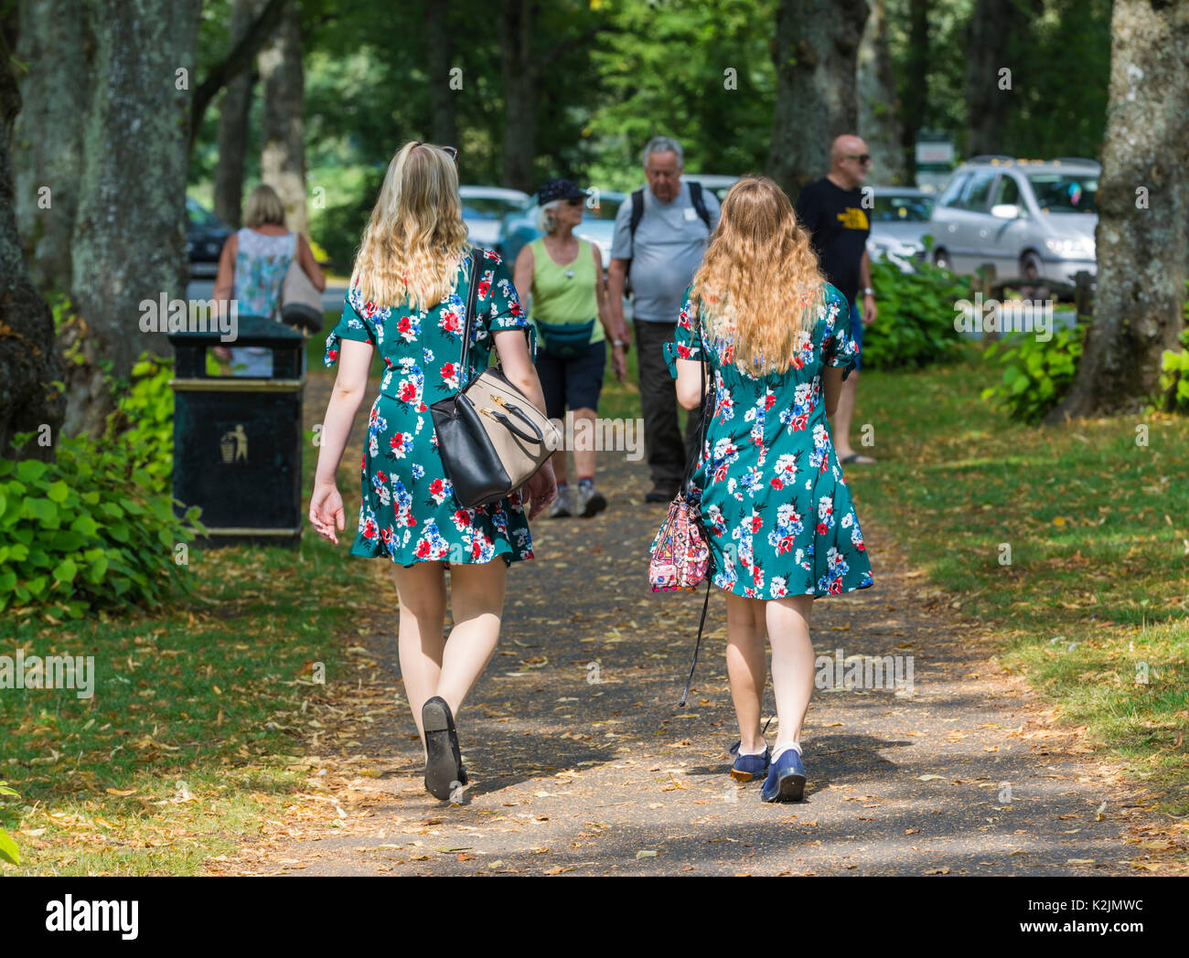 Par de jóvenes mujeres vestidas con idénticos vestidos de verano caminando en verano. 2 del tipo de concepto. Los gemelos. Nota: Las mujeres pueden o no estar relacionados. Foto de stock