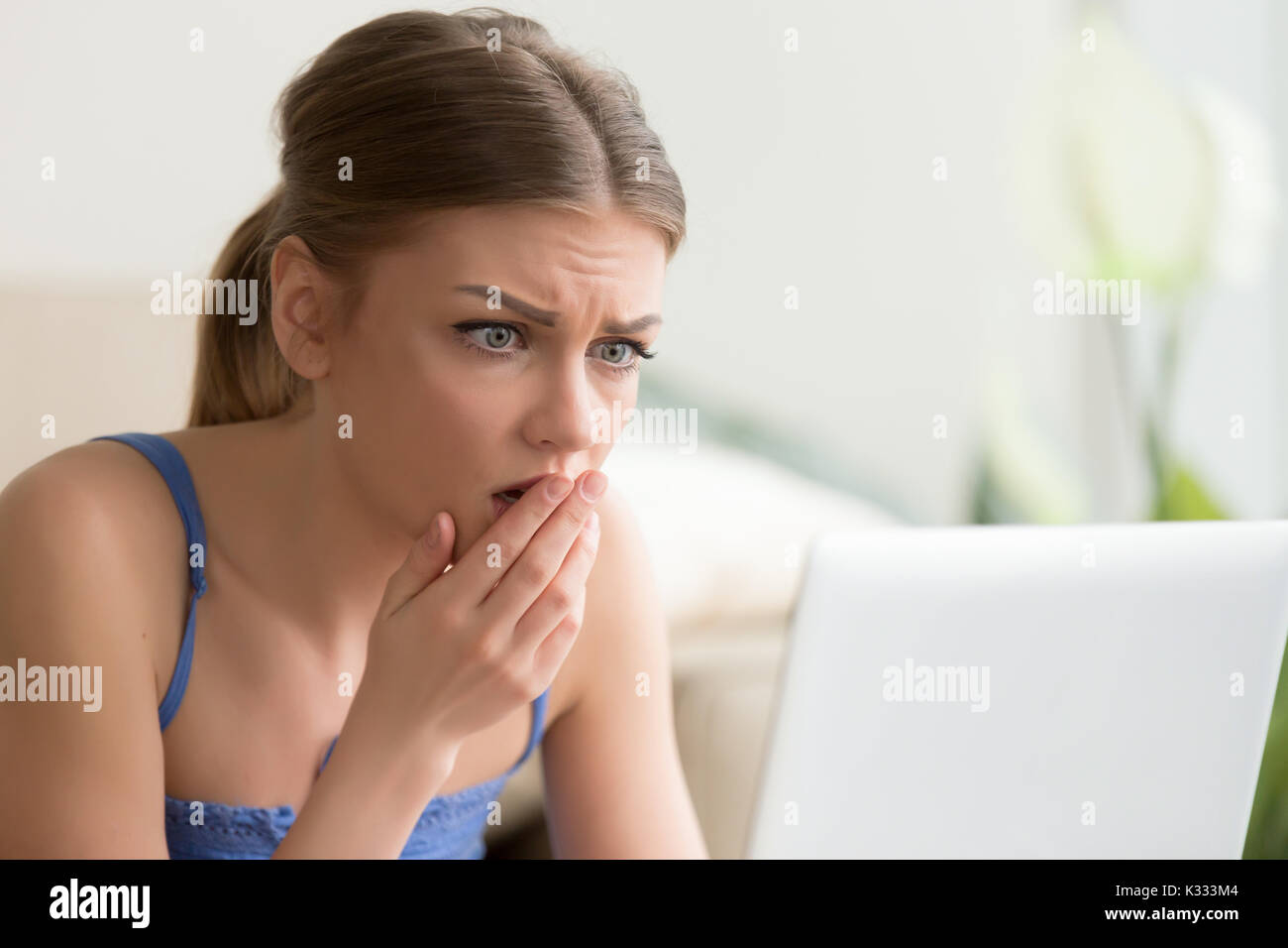 Mujer mirando en la pantalla de un ordenador portátil con miedo Foto de stock