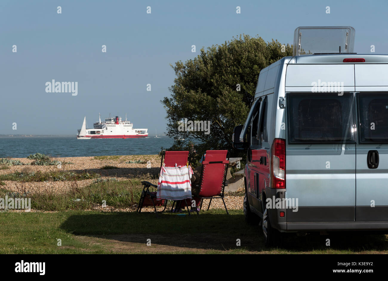 Camping junto al mar en el sur de Inglaterra. De agosto de 2017. Camperhome en una playa de guijarros con una vista de un buque Ro-Ro y el mar Foto de stock